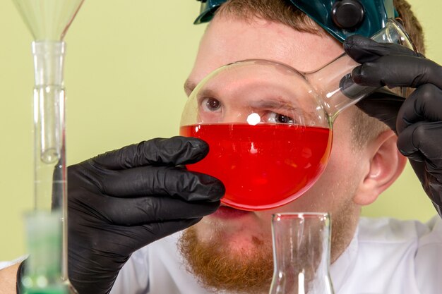 Vue de face jeune chimiste regardant si près de produit chimique