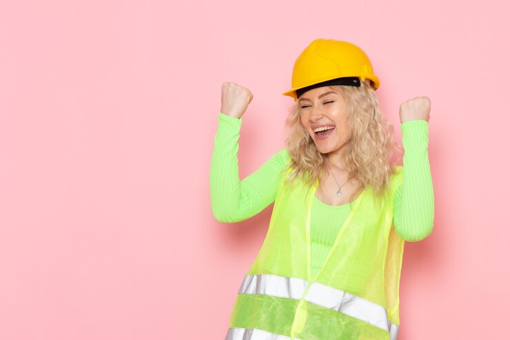 Photo gratuit vue de face jeune constructeur féminin en costume de construction verte casque expression heureuse sur les travaux de construction de l'architecture de l'espace rose