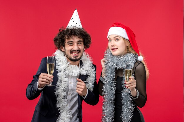 Vue de face jeune couple célébrant le nouvel an sur le bureau rouge aime la fête de Noël