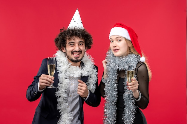 Vue de face jeune couple célébrant le nouvel an sur le bureau rouge aime la fête de Noël