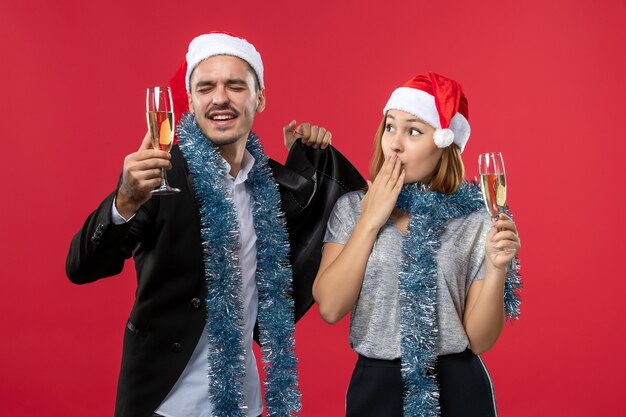 Vue de face jeune couple célébrant le nouvel an sur le bureau rouge aime la fête de Noël