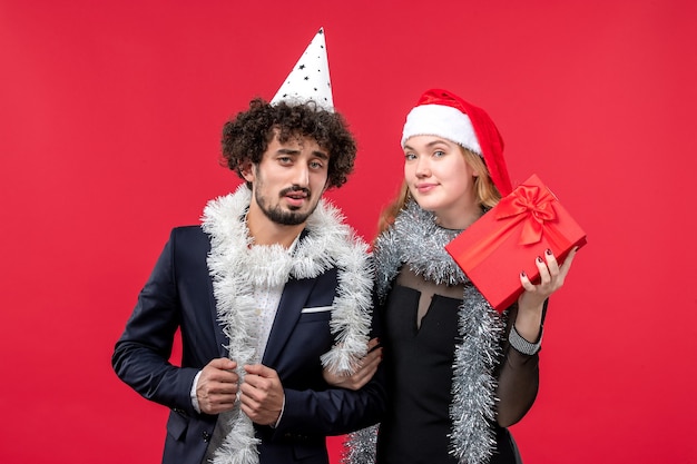 Vue de face jeune couple célébrant le nouvel an sur le bureau rouge vacances d'amour de Noël