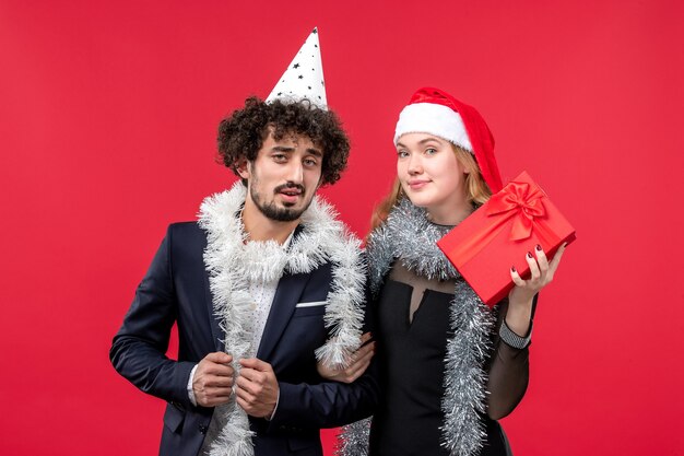 Vue de face jeune couple célébrant le nouvel an sur le bureau rouge vacances d'amour de Noël