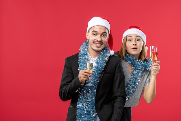 Vue de face jeune couple célébrant le nouvel an sur une fête de bureau rouge amour de Noël