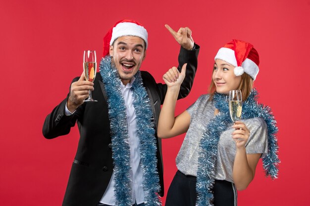 Vue de face jeune couple célébrant le nouvel an sur le mur rouge aime Noël