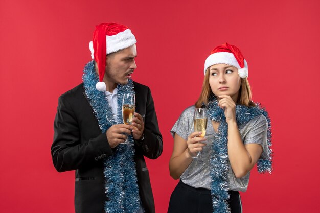 Vue de face jeune couple célébrant le nouvel an sur le mur rouge aiment les vacances de couleur de Noël