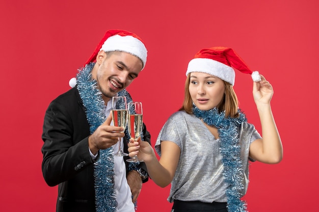 Vue de face jeune couple célébrant le nouvel an sur un mur rouge amour boisson de Noël