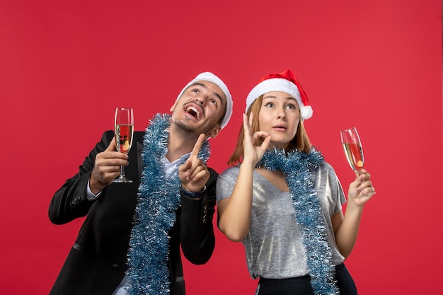 Vue de face jeune couple célébrant le nouvel an sur un mur rouge amour boisson de Noël