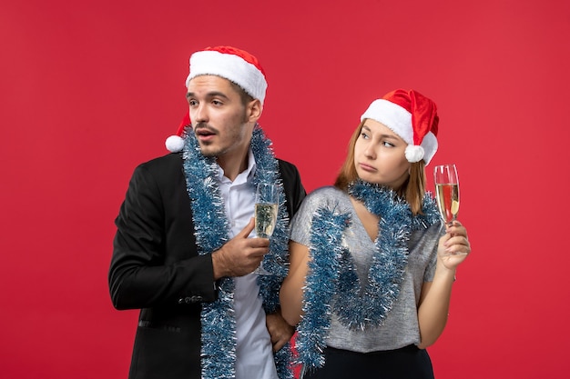 Vue de face jeune couple célébrant le nouvel an sur un mur rouge amour fête de Noël