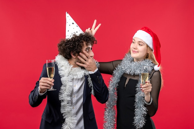 Vue de face jeune couple célébrant le nouvel an sur un mur rouge amour fête de Noël