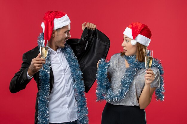 Vue de face jeune couple célébrant le nouvel an sur un mur rouge amour fête de Noël