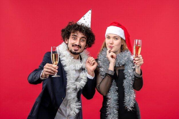 Vue de face jeune couple célébrant le nouvel an sur le mur rouge fête d'amour de Noël