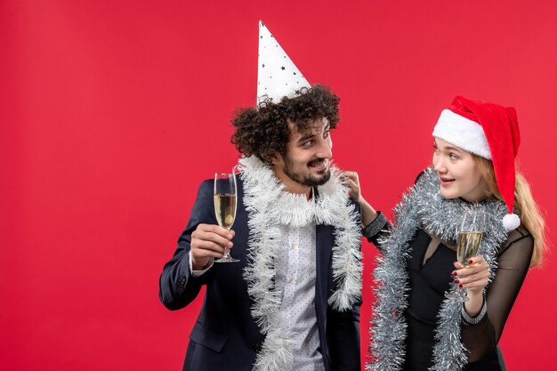Vue de face jeune couple célébrant le nouvel an sur un mur rouge vacances amour fête de Noël