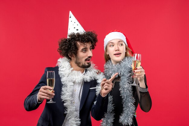Vue de face jeune couple célébrant le nouvel an sur le plancher rouge vacances Noël amour