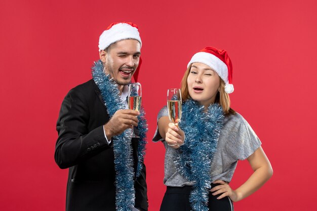 Vue de face jeune couple juste célébrer le nouvel an sur le mur rouge fête d'amour de Noël