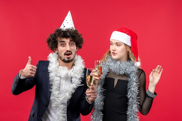 Vue de face jeune couple juste célébrer le nouvel an sur le mur rouge photo d'amour de Noël