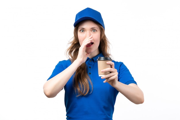 Une vue de face jeune courrier en chemise bleue casquette bleue tenant une tasse de café sur blanc