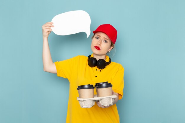 Vue de face jeune courrier en chemise jaune et cape rouge tenant des tasses à café panneau blanc sur l'espace bleu