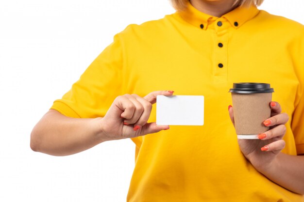 Une vue de face jeune courrier en chemise jaune tenant une carte blanche et une tasse de café