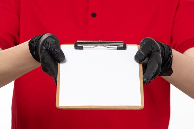 Une vue de face jeune courrier en chemise rouge et gants noirs tenant note papier