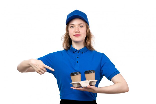 Une vue de face jeune courrier féminin en uniforme tenant des tasses avec café souriant