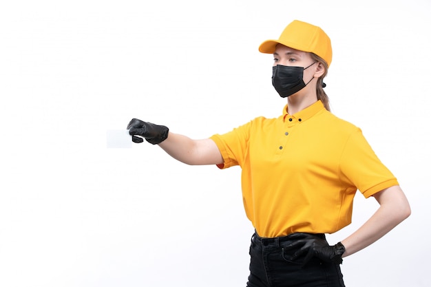 Une vue de face jeune courrier en uniforme jaune gants noirs et masque noir tenant une carte blanche