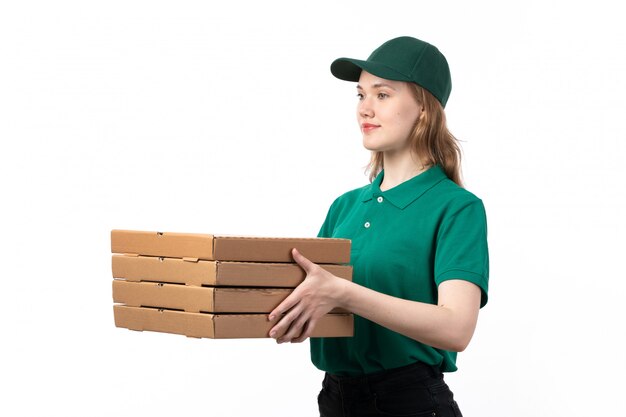 Une vue de face jeune courrier en uniforme vert livrant des boîtes avec pizza et souriant sur blanc