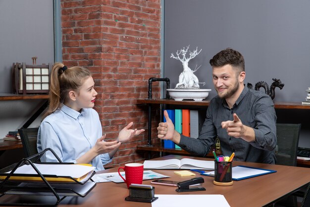 Vue de face d'une jeune équipe de bureau satisfaite assise à la table pour discuter d'un problème important au bureau