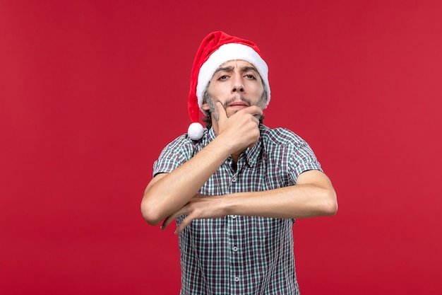 Vue de face jeune avec expression de la pensée sur le mur rouge vacances nouvel an rouge