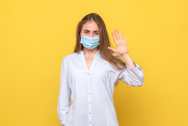 Vue de face d'une jeune femme agitant sur un mur jaune