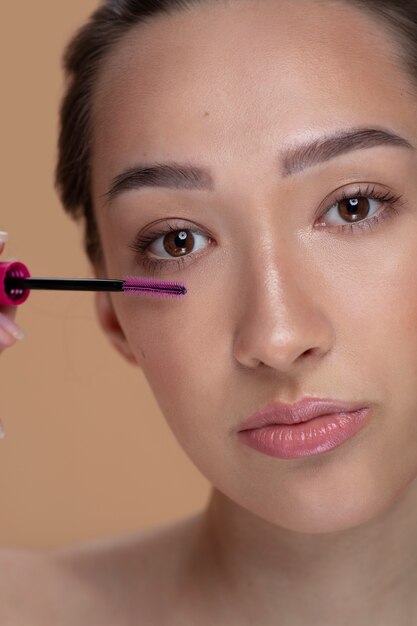 Vue de face jeune femme à l'aide de mascara