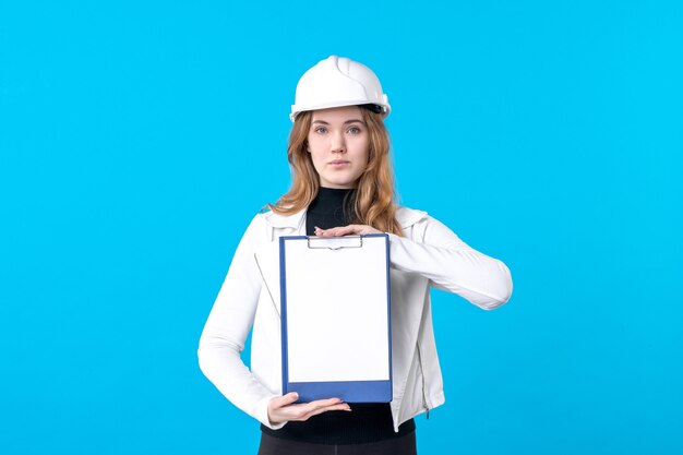 Vue de face jeune femme architecte tenant une note de dossier sur le bleu
