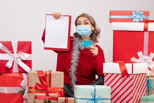 Vue de face jeune femme assise autour de cadeaux avec carte bancaire