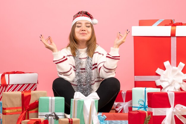 Vue de face jeune femme assise autour des cadeaux de Noël et méditer