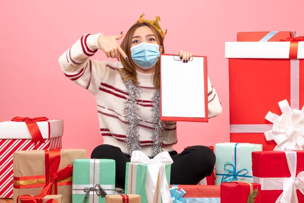 Vue de face jeune femme assise autour de cadeaux de Noël avec note de fichier