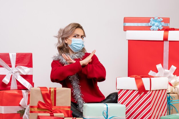 Vue de face jeune femme assise autour de cadeaux de Noël