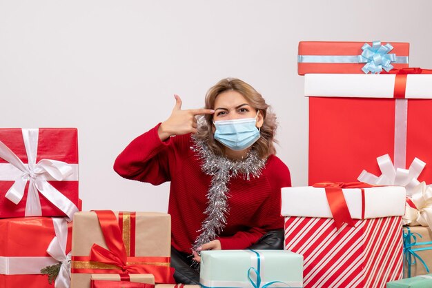 Vue de face jeune femme assise autour de cadeaux de Noël