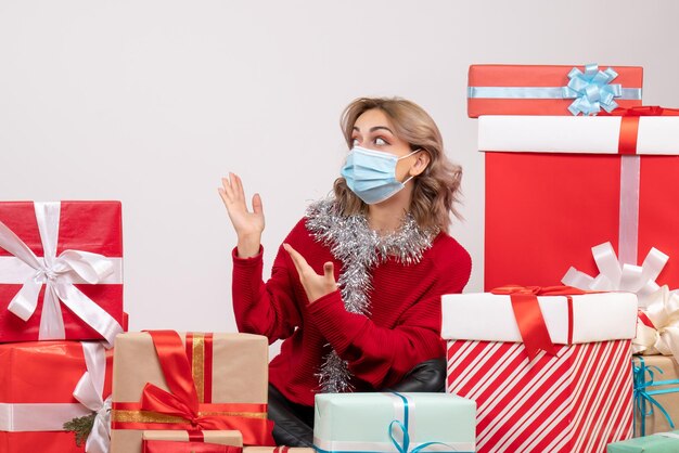 Vue de face jeune femme assise autour de cadeaux de Noël