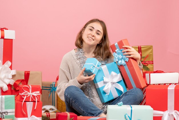 Vue de face jeune femme assise autour de cadeaux de Noël