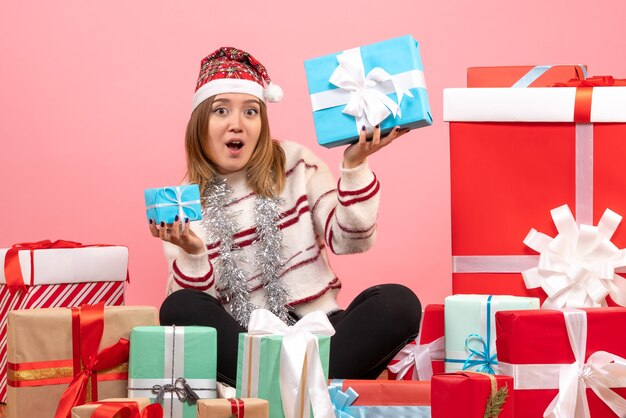 Vue de face jeune femme assise autour de cadeaux de Noël