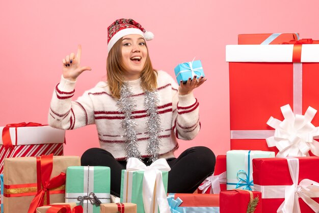 Vue de face jeune femme assise autour de cadeaux de Noël