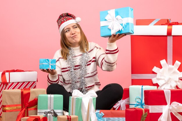 Vue de face jeune femme assise autour de cadeaux de Noël