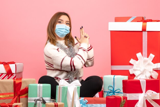 Vue de face jeune femme assise autour de cadeaux de Noël