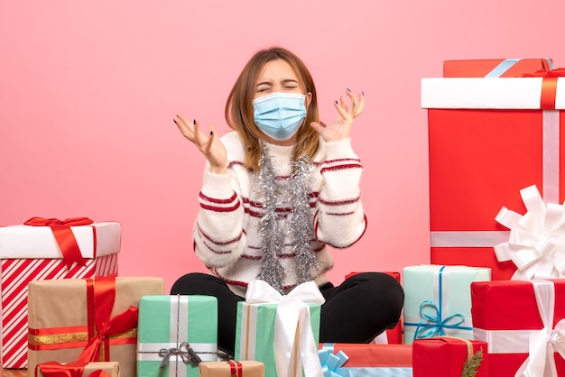 Vue de face jeune femme assise autour de cadeaux de Noël