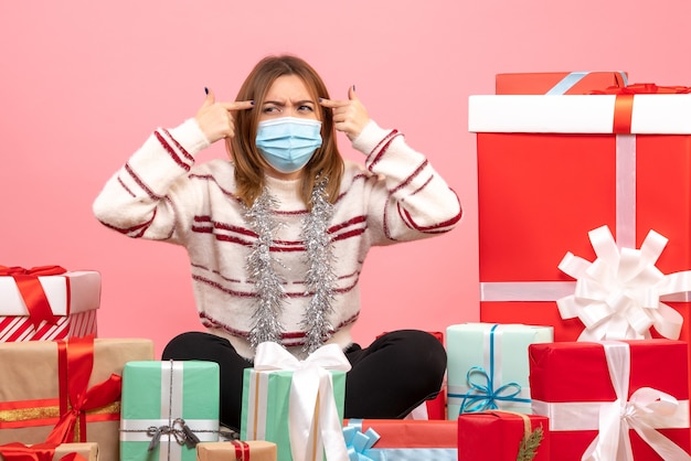 Vue de face jeune femme assise autour de cadeaux de Noël