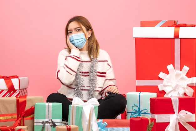 Vue de face jeune femme assise autour de cadeaux de Noël