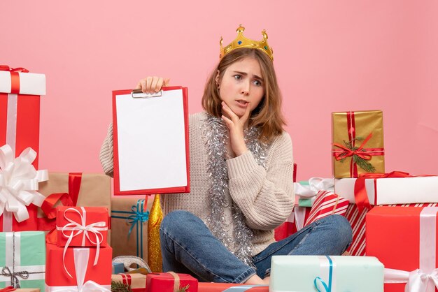 Vue De Face Jeune Femme Assise Autour De Cadeaux Avec Note Dans Ses Mains