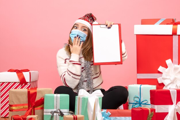 Vue de face jeune femme assise autour de cadeaux avec note de fichier