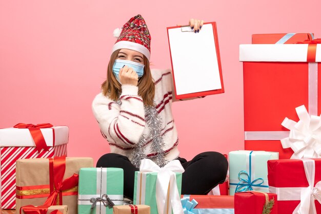 Vue de face jeune femme assise autour de cadeaux avec note de fichier