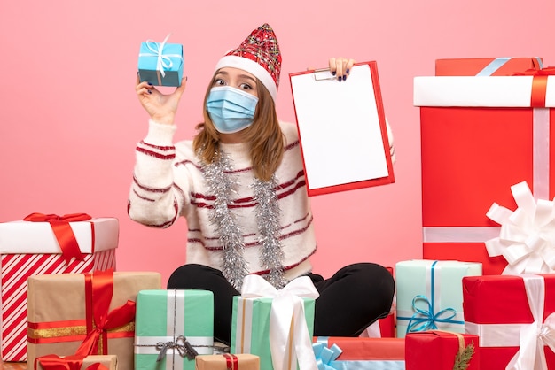 Vue de face jeune femme assise autour de cadeaux avec note de fichier